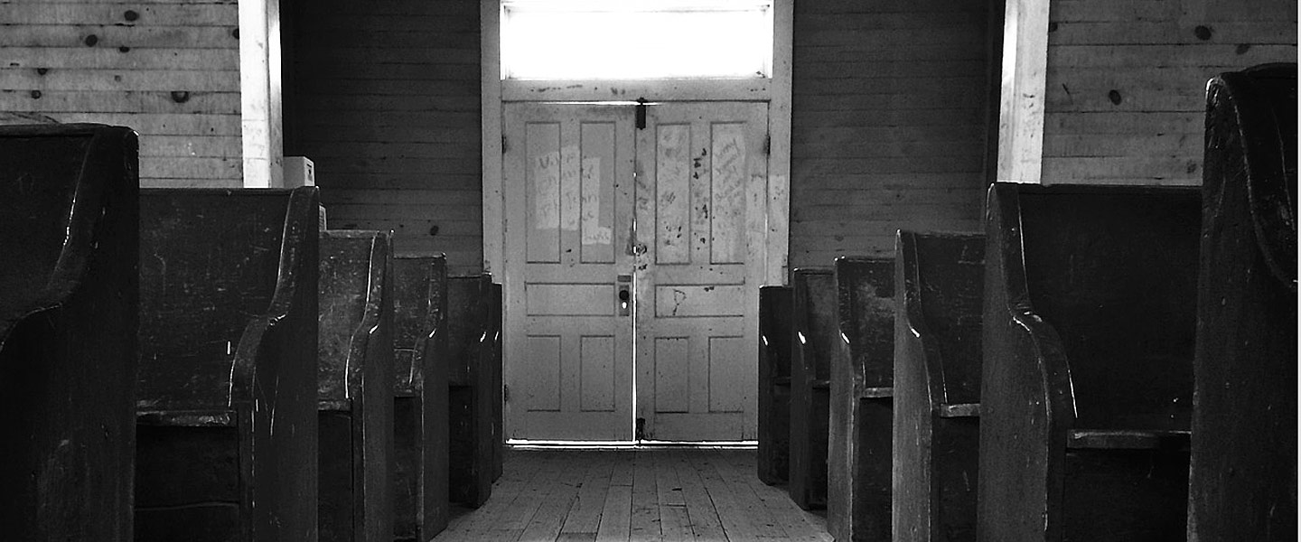 Picture of a church aisle with the doors at the centre and pers either side